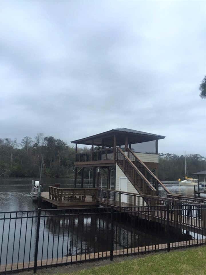 Two-story boathouse with metal roof, upper deck and enclosed storage room seen from the yard