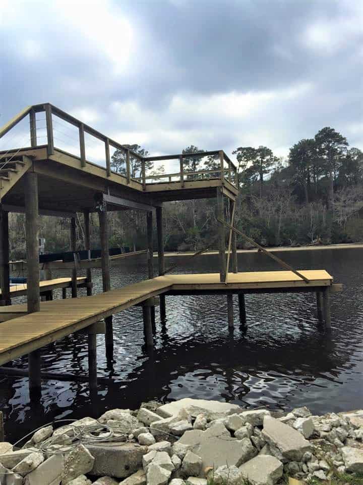 Elevated dock with upper sun deck, walkway and boat lift over dark river water