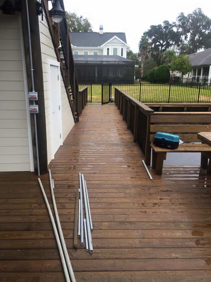 Wet dock decking and railed walkway running past a boathouse storage room toward the lawn