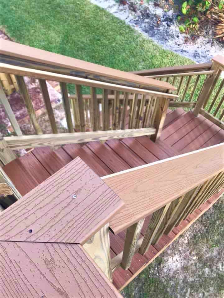 Overhead view of composite deck stairs and landing framed with pressure-treated railings above a lawn