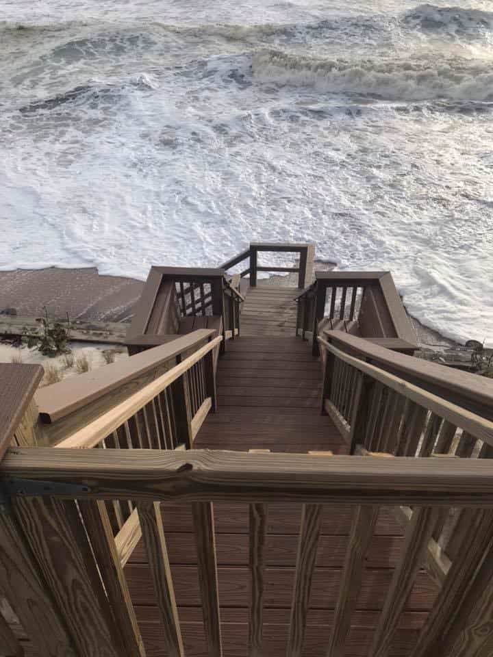 Beach walkover stairs and landing descending toward heavy surf, composite treads with wood railings