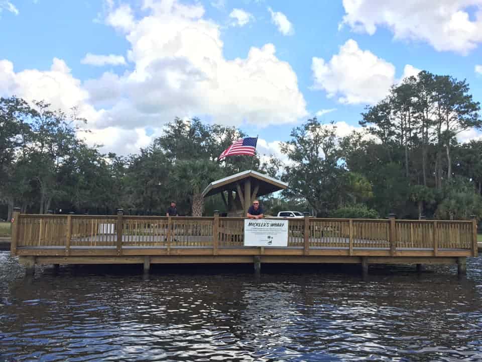 Railed public wharf platform with a small pavilion and American flag, seen from the water