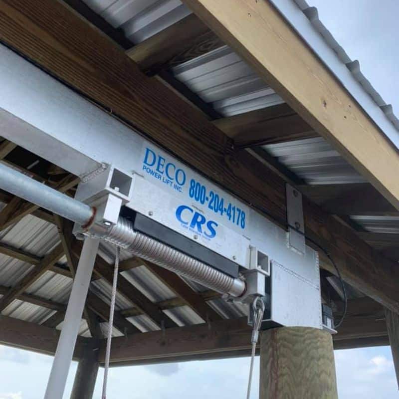 Underside of a boathouse roof showing a DECO power lift beam, cable drum and metal decking