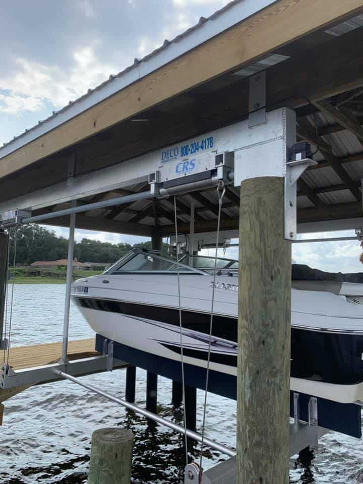 Navy and white cuddy cabin boat held on a lift under a metal boathouse roof
