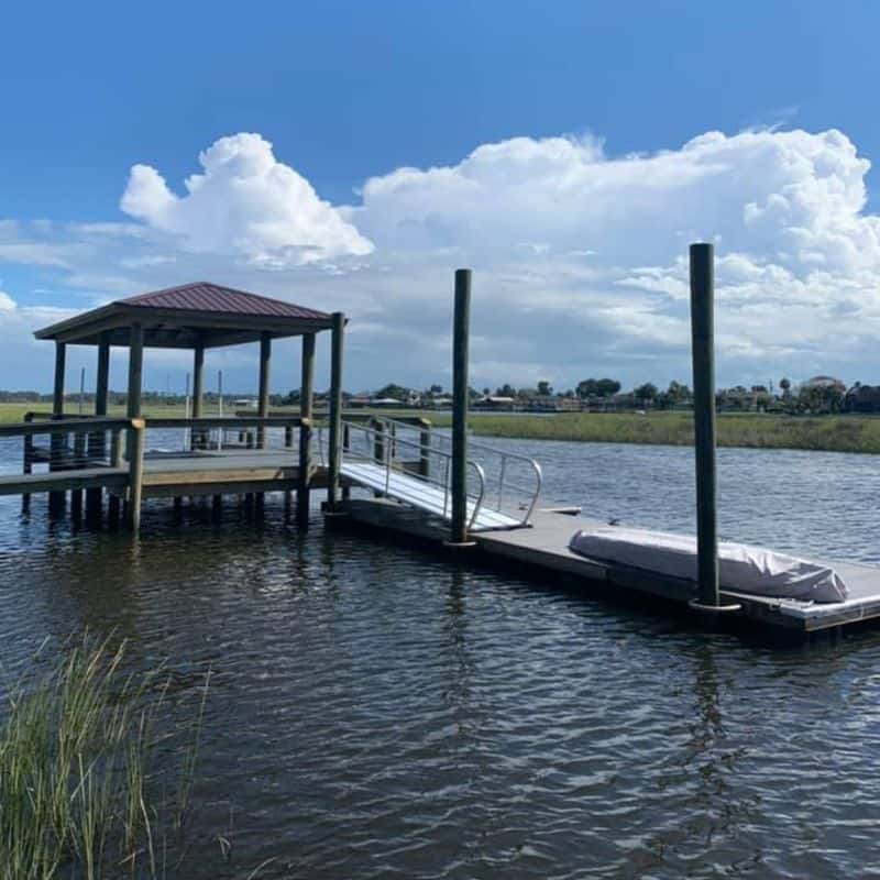 Small covered dock with red metal roof, aluminum gangway and floating dock on a tidal creek