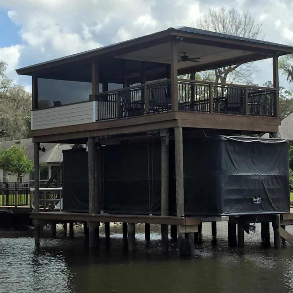 Two-story boathouse with metal roof, ceiling fan, railed upper deck and covered boat slip below