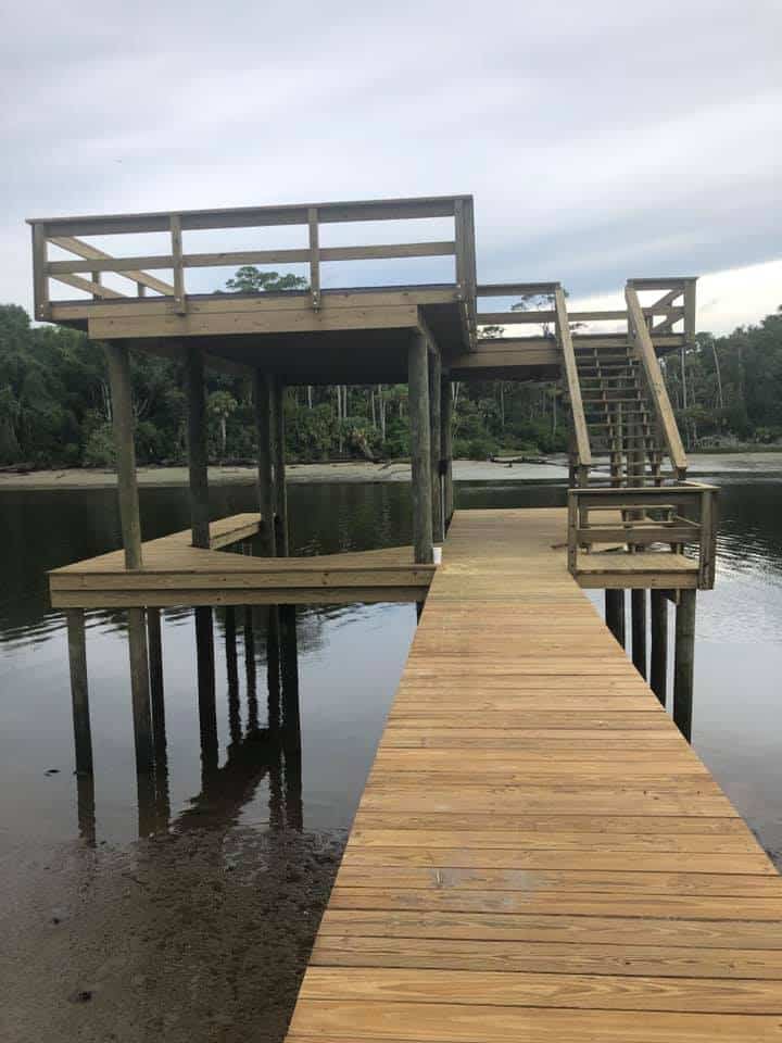 Finished two-level dock with upper sundeck, stair tower and long walkway over still water