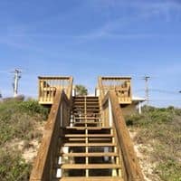 Wood dune walkover stairs climbing between two railed landings over coastal vegetation